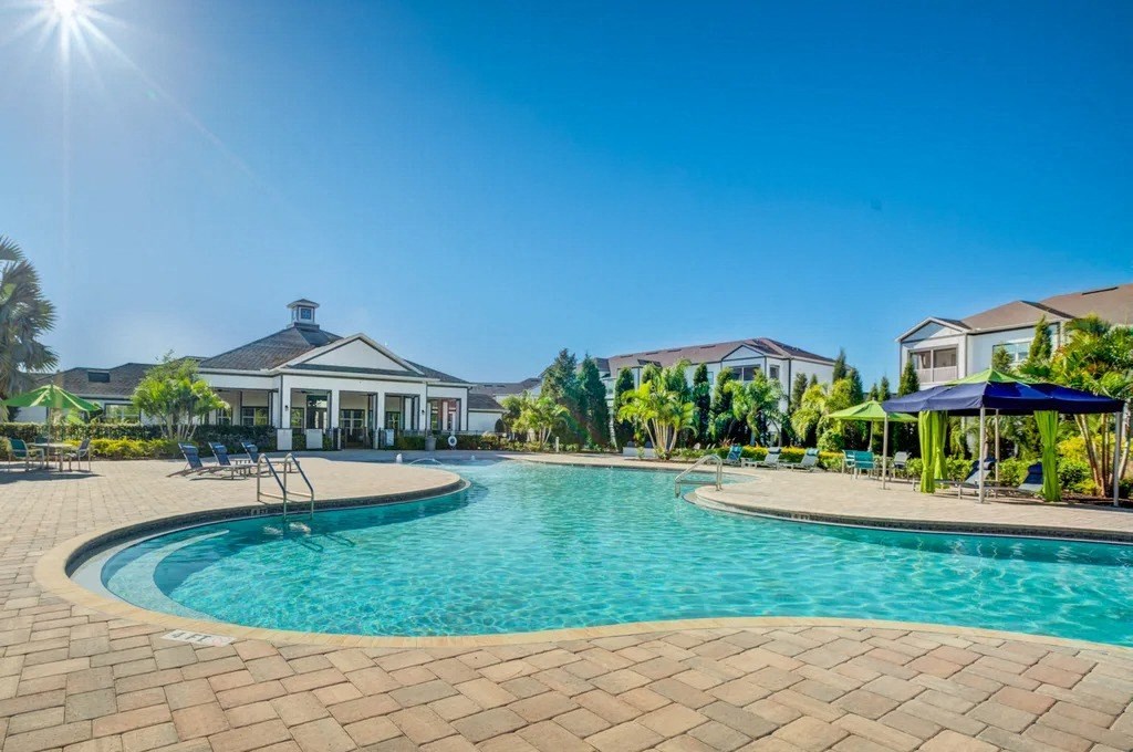 A large swimming pool surrounded by a brick patio and a house in the background.at Century Ariva, Lakeland, Florida  