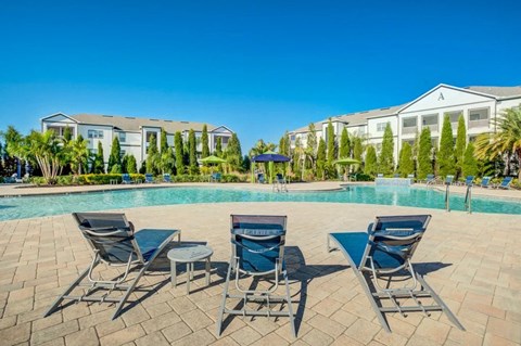 A pool surrounded by chairs and trees with a building in the background.at Century Ariva, Florida, 33812