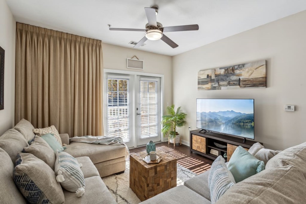 A living room with a grey couch and a flat screen TV.at Century Hampton Roads, Suffolk Virginia  