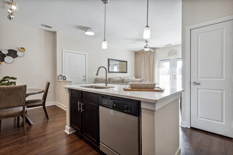 A modern kitchen with a black dishwasher and a wooden floor.
