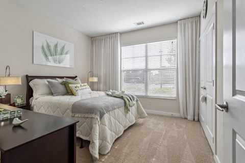 A bedroom with a large bed and a window with blinds.at Century Hampton Roads, Suffolk, VA