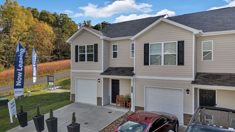 A house with a garage and a car parked in front.