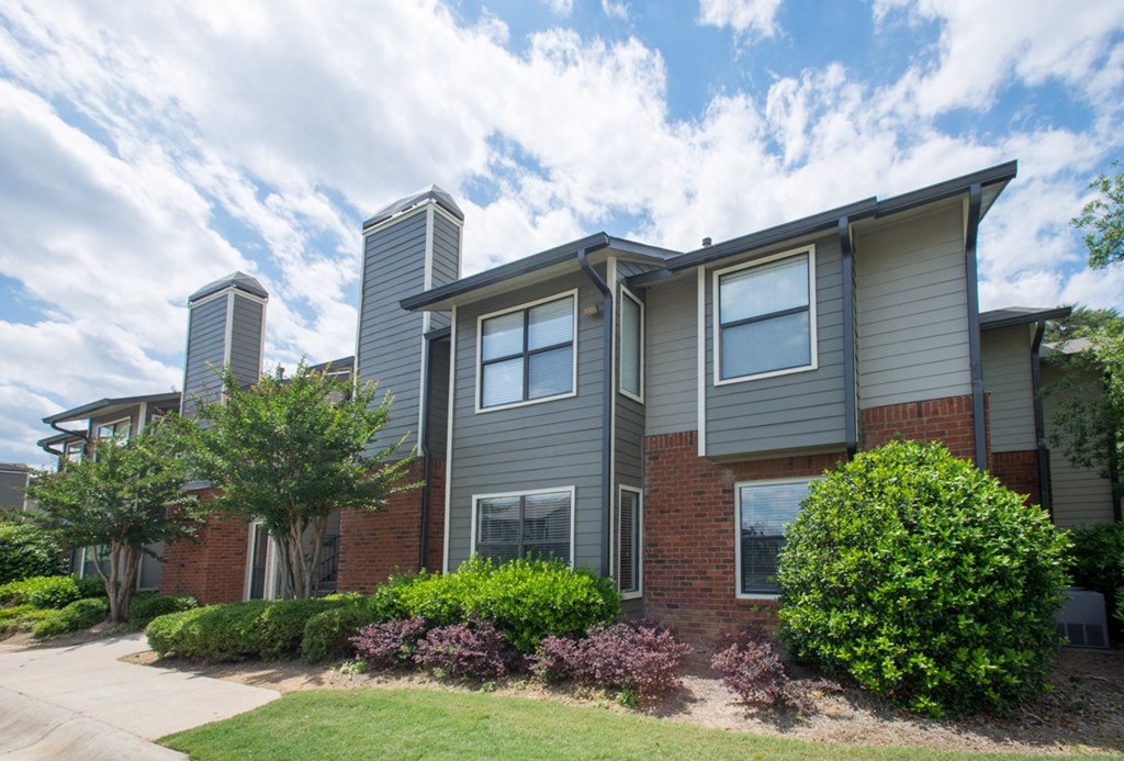 A grey house with a red brick base and a grey roof at Ridge Crossings Apartments, Alabama