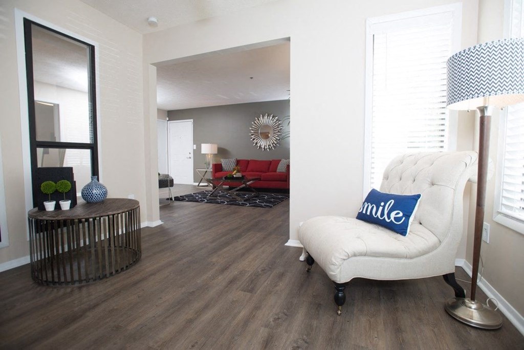 A living room with a white chair and a blue pillow that says smile at Ridge Crossings Apartments, Hoover, AL 35244