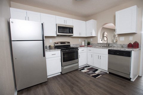 A kitchen with white cabinets and a refrigerator.