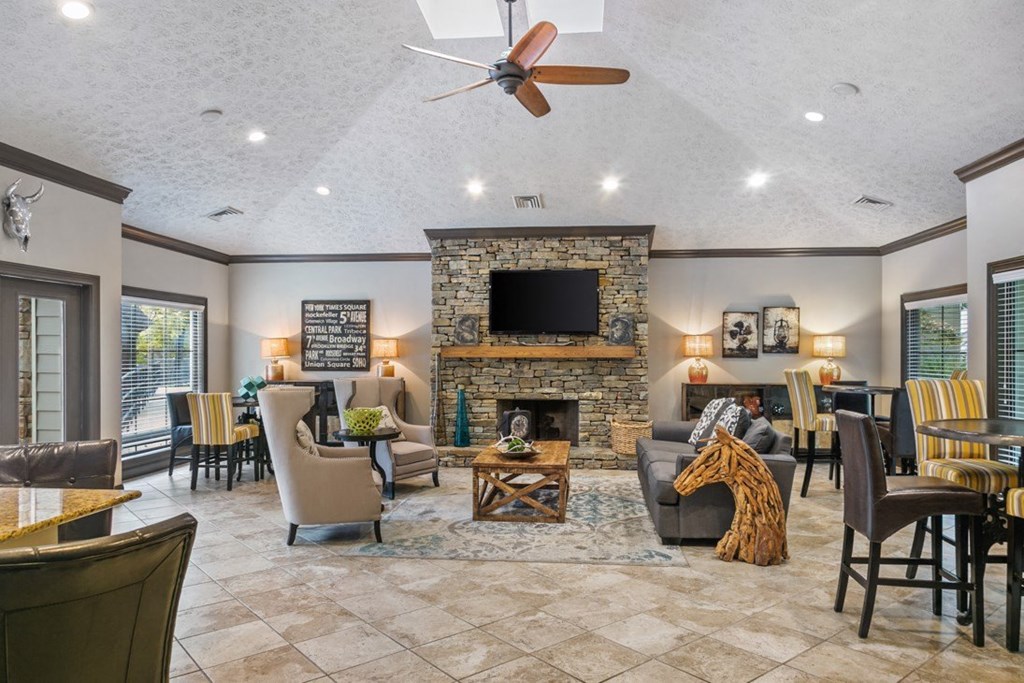 A living room with a stone fireplace and a flat screen TV at Ridge Crossings Apartments, Hoover