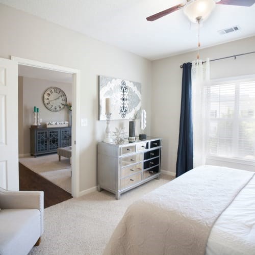 A bedroom with a large bed and a dresser with a mirror above it.