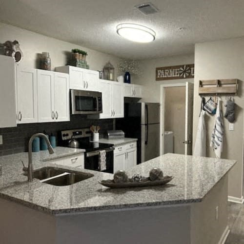 A kitchen with granite countertops and white cabinets.