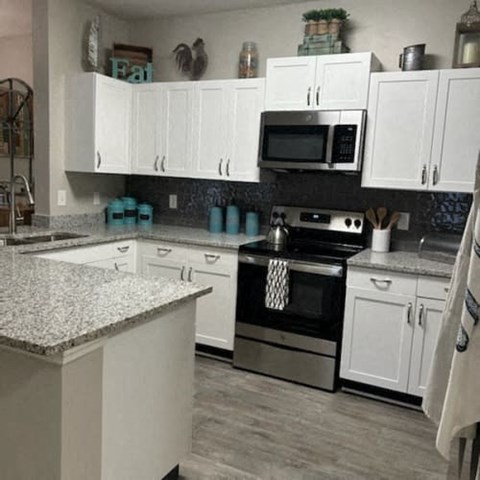 A kitchen with white cabinets and a granite countertop.