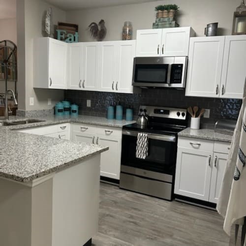 A kitchen with white cabinets and a granite countertop.