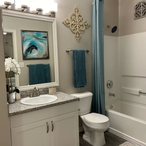 A bathroom with a white toilet, a white sink, and a blue shower curtain.
