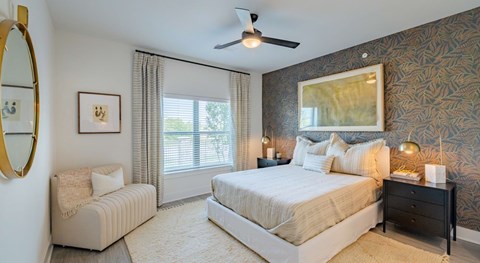 A bedroom with a large bed, a chair, and a ceiling fan.