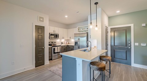 A modern kitchen with a large island and stools.