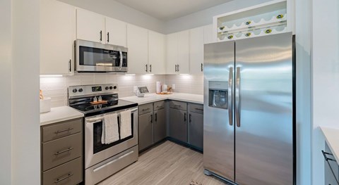 A modern kitchen with stainless steel appliances and wooden flooring.