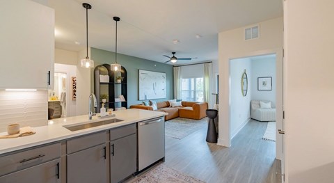 A modern kitchen with a dining area in the background.