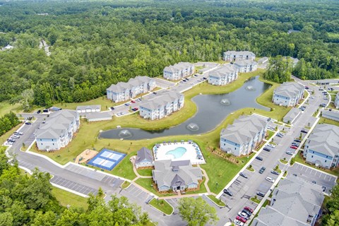 A bird's eye view of a residential area with houses, roads, and a small lake.