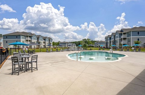 A large outdoor pool surrounded by chairs and apartment buildings.
