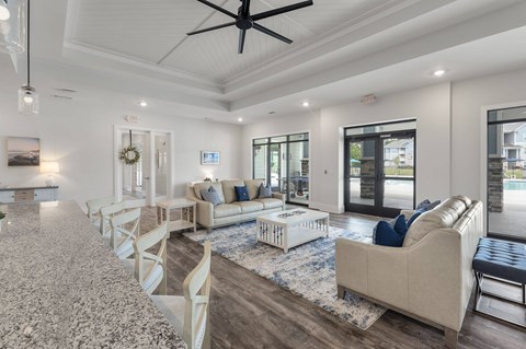 A spacious living room with a long white sofa and a rug.