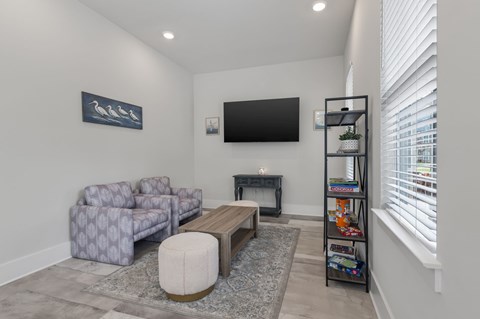 A living room with a grey sofa, a wooden coffee table, a TV, and a bookshelf.