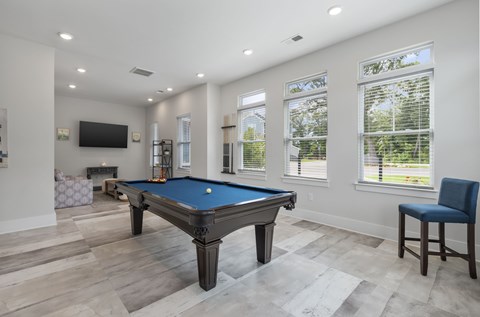 A pool table in a room with a television and a chair.