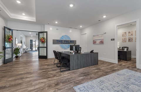 A reception area with a desk and chairs in front of a sign that says "The Palms".