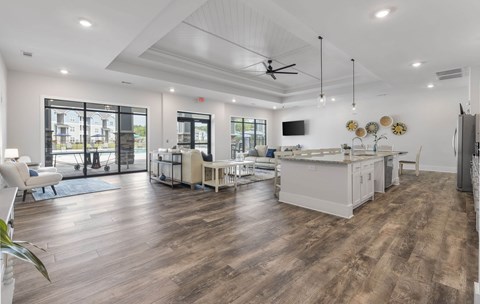 A spacious kitchen and living room with wooden floors and white furniture.