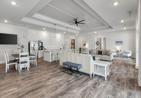 A spacious living room with a white sofa set and a wooden floor.