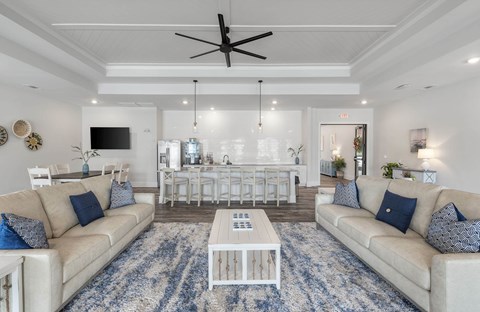 A living room with a white ceiling fan and a blue patterned rug.