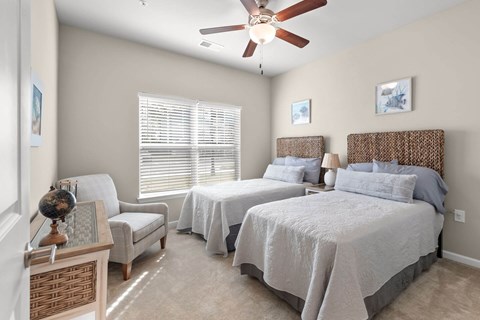A bedroom with two beds and a ceiling fan.