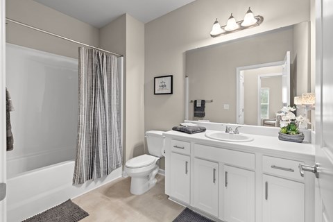 A white bathroom with a toilet, sink, and shower.