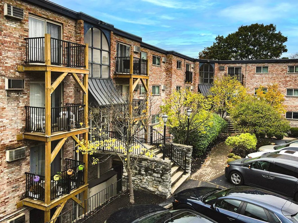 A brick building with a balcony and a tree in front.