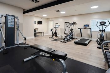 A gym with a variety of equipment including treadmills, weights, and exercise machines.