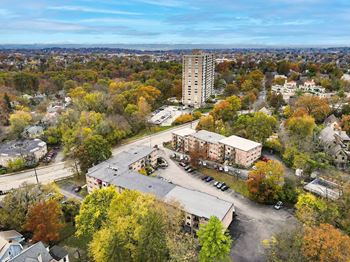 A tall building stands in the middle of a parking lot surrounded by trees with autumn leaves.