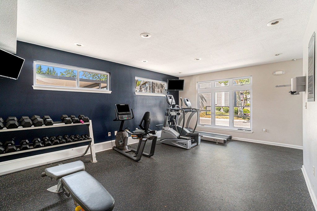 A spacious home gym with a bench, weights, and exercise equipment.