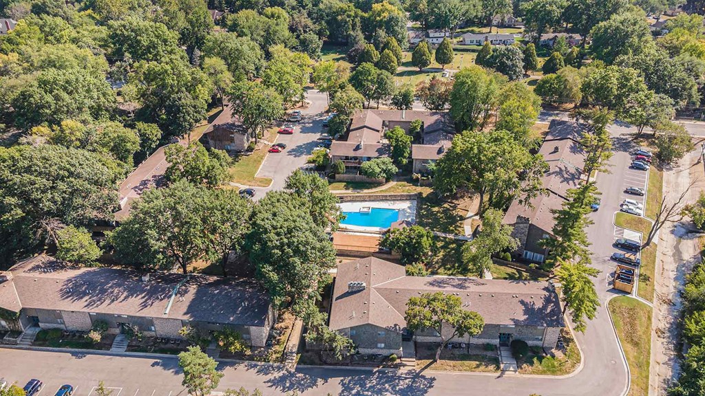 A bird's eye view of a residential area with houses and a swimming pool.