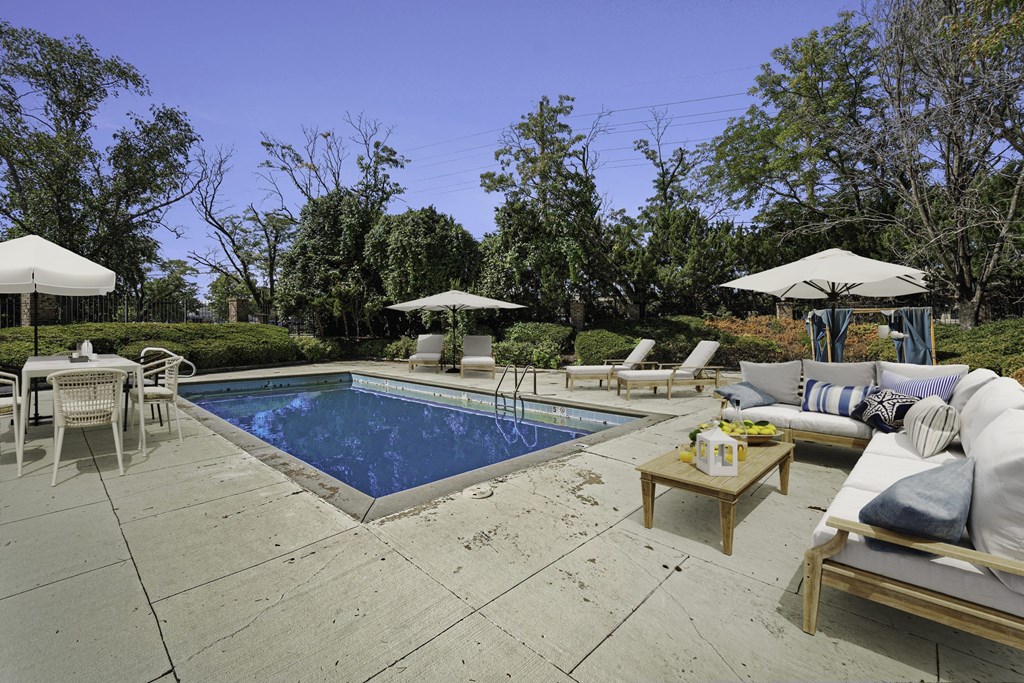 A pool surrounded by patio furniture and umbrellas.