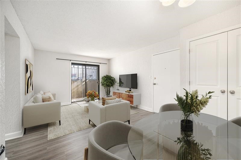 A modern living room with a glass table and grey chairs.