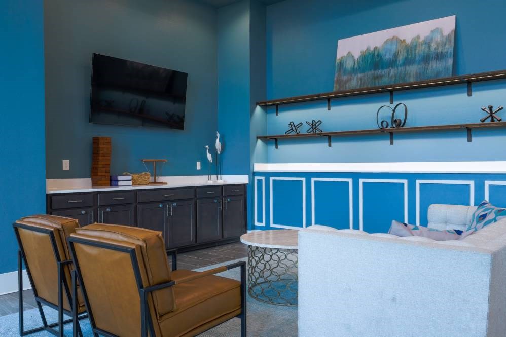 A blue kitchen with brown chairs and a white counter.