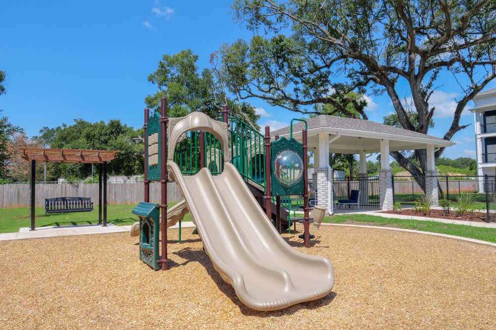 A playground with a green slide and a brown sandbox.