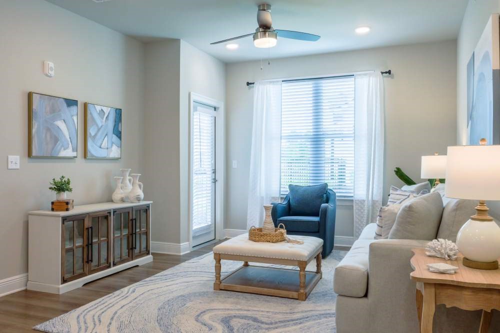 A living room with a grey couch, a wooden coffee table, and a ceiling fan.