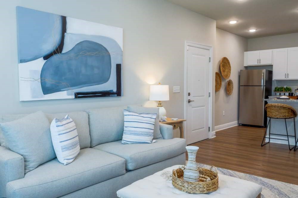 A living room with a grey couch and a painting on the wall.