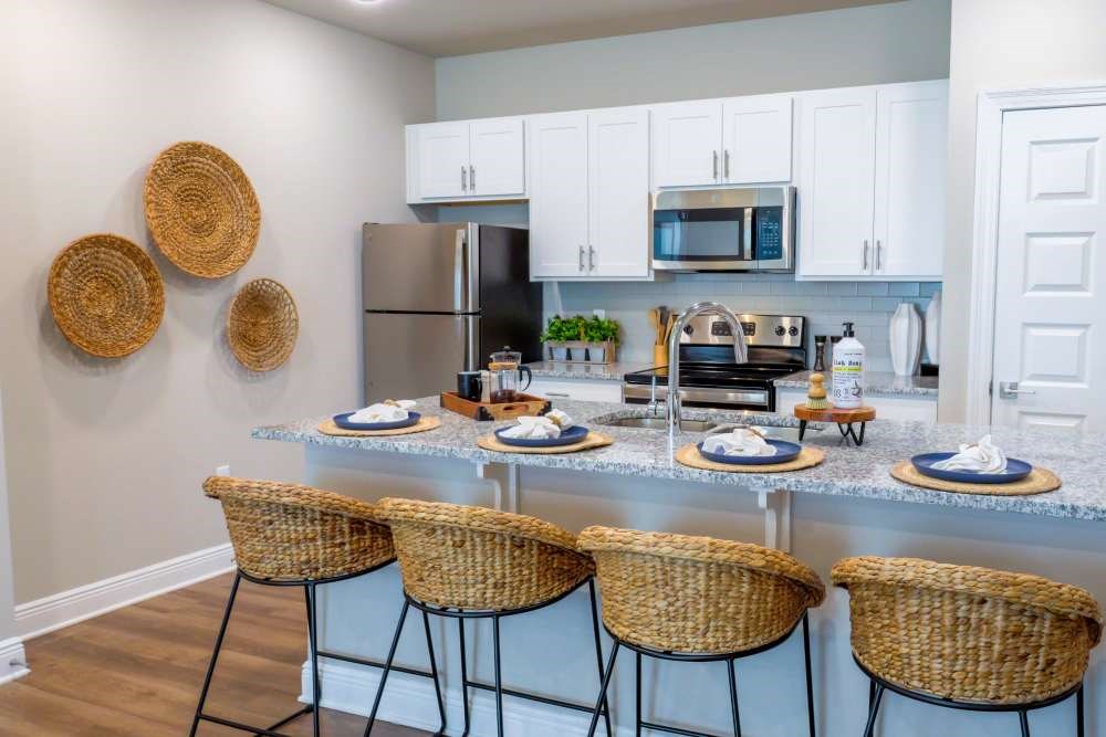 A kitchen with a white countertop and wicker chairs.