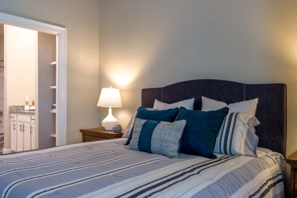 A bed with a blue and white striped comforter and a black headboard with four pillows.