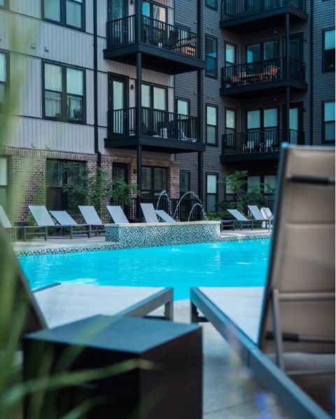 A pool area with lounge chairs and a building in the background.