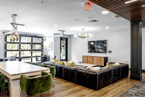 A modern bedroom with a large bed and a dining area with green chairs.