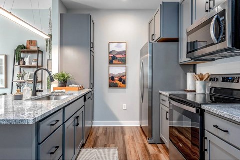 A modern kitchen with dark grey cabinets and a marble countertop.
