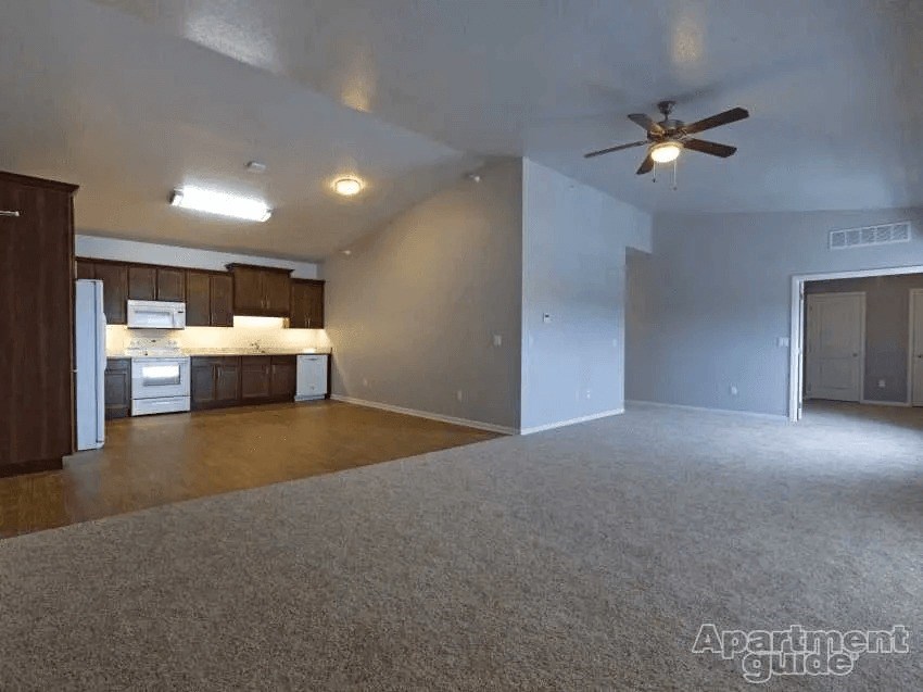 Apartment living room with a ceiling fan and a carpeted floor.