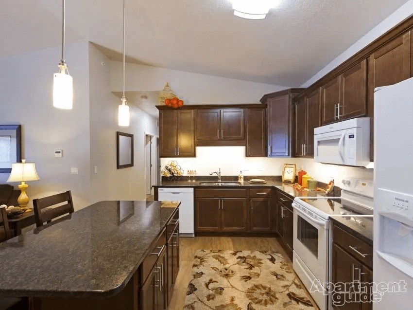 A kitchen with brown cabinets and a black countertop.