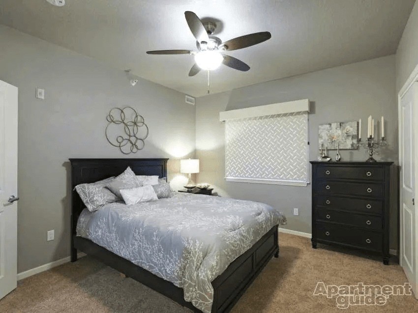 A bedroom with a bed, dresser, and ceiling fan.