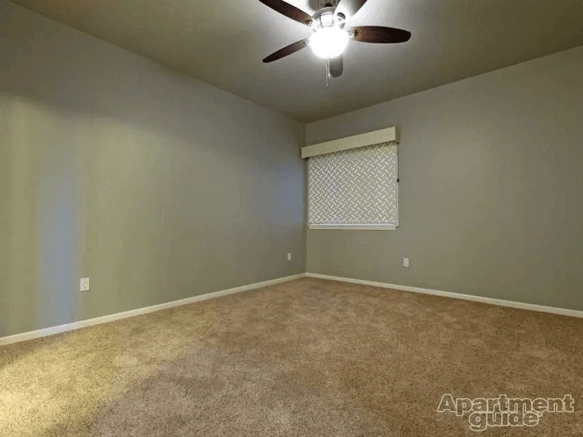 A room with a ceiling fan and a window with blinds.